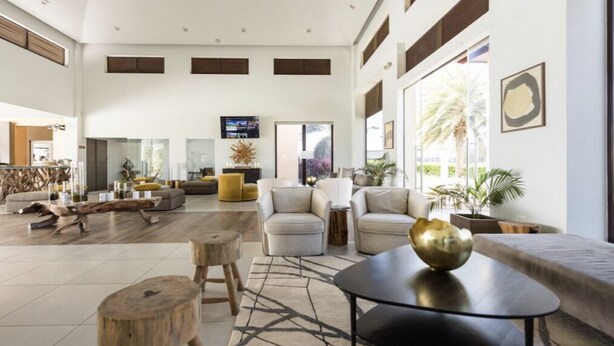 A spacious living room with a high ceiling, large windows, and a modern interior design. - Casa de Pauline - Noord (Noord)