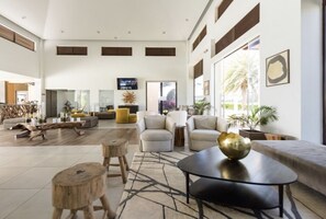 Een ruime woonkamer met een hoge plafond, grote ramen en een modern interieur.