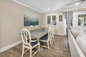 Un coin repas avec une table et des chaises, un tableau accroché au mur et une fenêtre avec des rideaux.