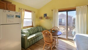 Ein gemütlicher Wohnraum mit Küchenzeile, einem grün gestreiften Sofa, einem Esstisch mit Stühlen und einem Balkon mit Blick.