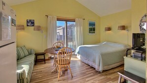 Ein Zimmer mit einem Bett, einer Couch, einem Esstisch mit Stühlen, einem Deckenventilator und einem Fernseher.