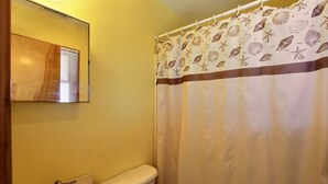 Ein Badezimmer mit Toilette, Waschbecken und einer Duschkabine mit Muschelmuster.