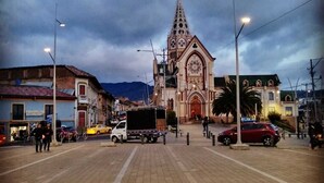 Una calle con una iglesia destacada, un camión y un coche rojo.