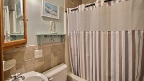 A bathroom with a toilet, sink, and bathtub. There is a shower curtain with vertical stripes. - Ocean's Door East is fun for the whole family! (HATTERAS)