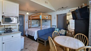 A compact room with a bunk bed, a kitchenette, a dining table, and a TV. - Ocean's Door East is fun for the whole family! (HATTERAS)