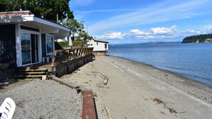 Une propriété située au bord de l’eau, dotée d’une terrasse en bois, d’un bâtiment aux grandes fenêtres et offrant une vue sur l’eau.