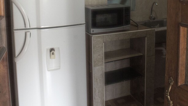 A compact kitchen with a white refrigerator, a microwave, and a sink. - Guest House Yuraq Wasi (Cusco)