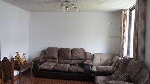 A living room with a brown sofa, a wooden side table, and a ceiling fan. - Guest House Yuraq Wasi (Cusco)