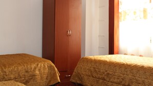 A bedroom with two beds, a wardrobe, and a window with curtains. - Guest House Yuraq Wasi (Cusco)