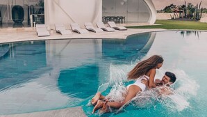 A modern pool area with a unique architectural design, including a curved building and lounge chairs. - The Cloud Unique Beachfront Villa (Tabanan)