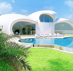 A modern architectural building with a pool and lounge chairs. - The Cloud Unique Beachfront Villa (Tabanan)