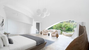 A modern bedroom with a large bed, a view of the garden, and a unique ceiling design. - The Cloud Unique Beachfront Villa (Tabanan)