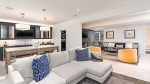 Ein modernes Wohnzimmer mit einem Ecksofa, einem Essbereich und einer Küche mit einer großen Kochinsel.