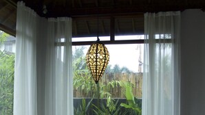Mesa de madera dispuesta con vajilla blanca y un farol, con vistas a la vegetación.