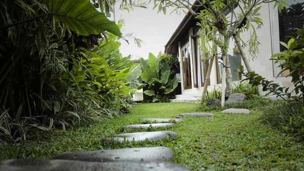 Un camino de piedra que lleva a un edificio rodeado de abundante vegetación.