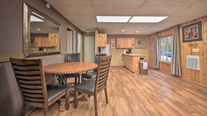 A dining area with a wooden table and chairs, a kitchen area with wooden cabinets, and a large mirror on the wall. - ‘John Wayne' Apartment - Deck, BBQ, Horses On-Site (Huntingdon)