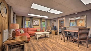 A living room with a red sofa, wooden coffee table, and a dining area with a table and chairs. - ‘John Wayne' Apartment - Deck, BBQ, Horses On-Site (Huntingdon)