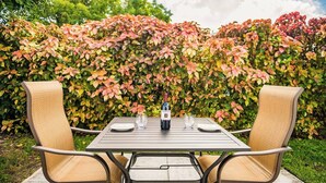 An outdoor patio with a table and two chairs, a bottle of wine, and glasses. - #4 ❤️ Sunny, Newly Furnished 1BR apt (Fort Lauderdale)