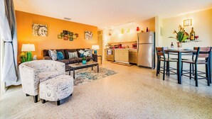 A modern living room with a sofa, coffee table, and ottoman, a kitchen with a refrigerator and microwave, and a dining area with chairs and a table. - #4 ❤️ Sunny, Newly Furnished 1BR apt (Fort Lauderdale)