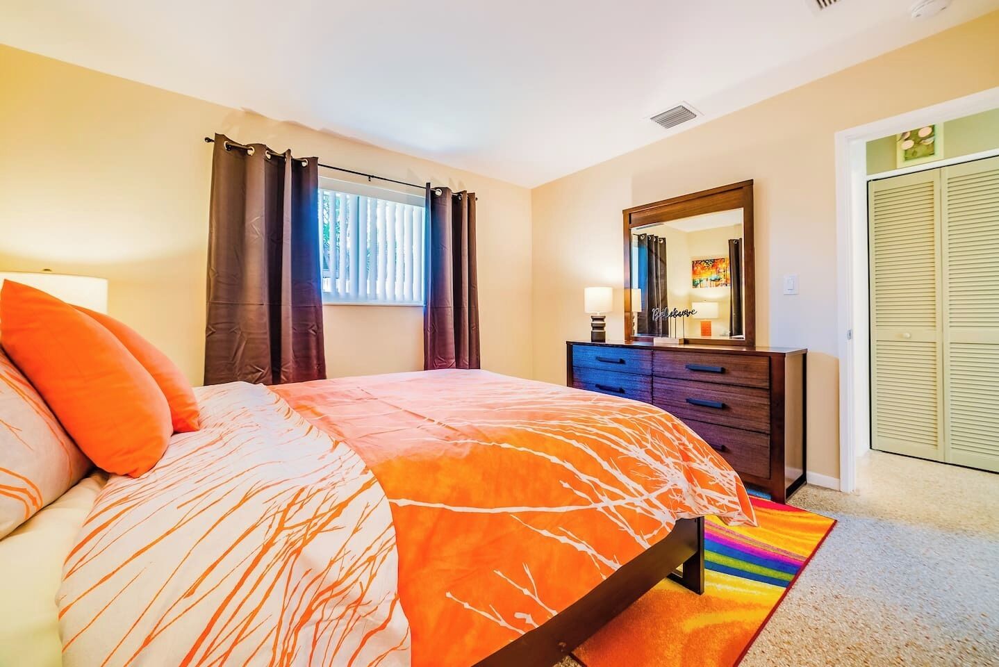 Un dormitorio con cama, cómoda, espejo y armario.