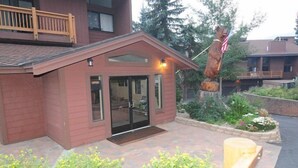 A red building with a glass door entrance, a small porch, and a wooden railing.