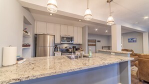 A modern kitchen with stainless steel appliances, granite countertops, and pendant lighting.
