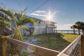 A coastal house with a balcony, a fenced yard, and a view of the ocean.