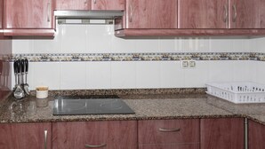 A kitchen with wooden cabinets, a granite countertop, a built-in stove, and a white tiled backsplash. - LIDER, 10-B (Cullera)