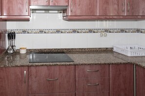 A kitchen with wooden cabinets, a granite countertop, a built-in stove, and a white tiled backsplash.