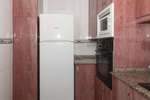 A compact kitchen with a white refrigerator, a microwave, and a stove.