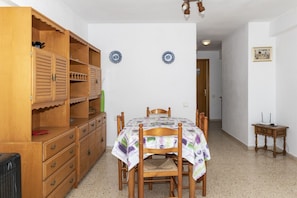 Ein Essbereich mit einem Holzhocker, einem runden Tisch mit Stühlen und zwei dekorativen Tellern an der Wand.