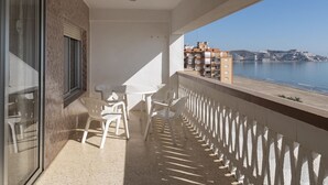 A balcony with a table and chairs, overlooking a coastal area with buildings and a body of water. - LIDER, 10-B (Cullera)
