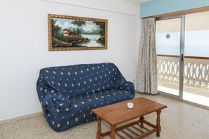 Ein Zimmer mit einem blauen Sofa, einem Holztisch und einem Landschaftsbild.