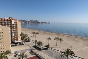 Ein Hotel direkt am Strand mit Meerblick, einem Parkplatz und einer Promenade mit Palmen.