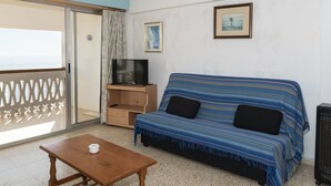 A room with a sofa, a TV on a wooden stand, a small table, and a picture on the wall. - LIDER, 10-B (Cullera)