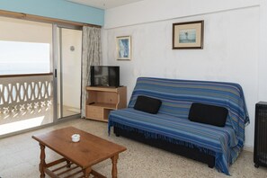 A room with a sofa, a TV on a wooden stand, a small table, and a picture on the wall. - LIDER, 10-B (Cullera)