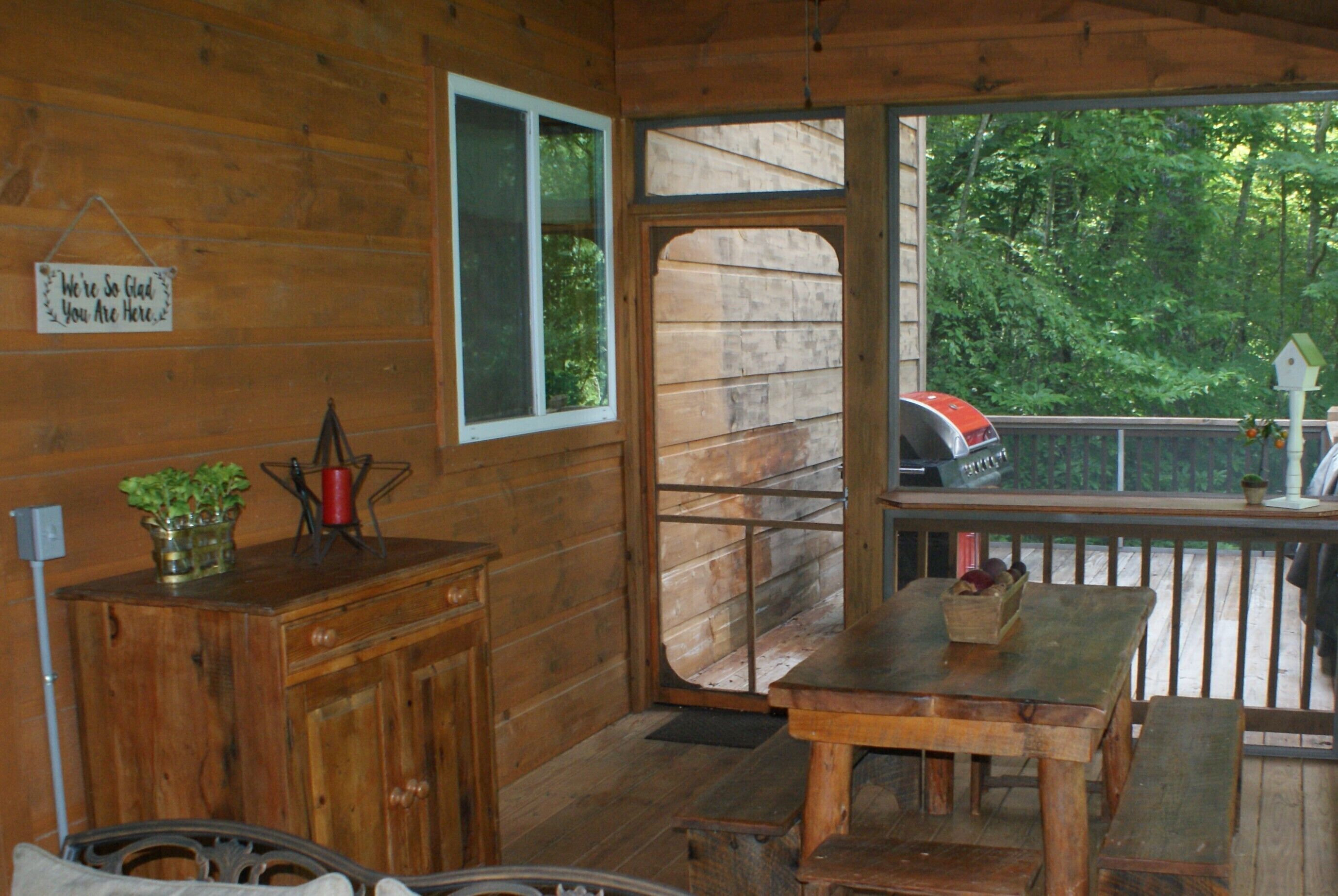 Interior de una cabaña de madera con una mesa, un banco, un armario y una ventana.