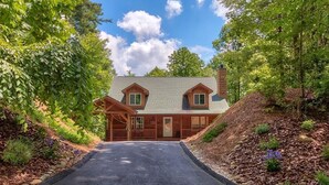 A two-story house with a covered porch, a driveway, and a landscaped garden. - Peaceful Mountain Cabin (Sapphire)