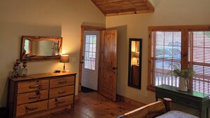 A bedroom with a wooden ceiling, a ceiling fan, a bed, a dresser, a mirror, and a window with blinds. - Peaceful Mountain Cabin (Sapphire)