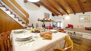 A dining area with a wooden staircase, a dining table set with plates, glasses, and bread, and a sofa in the background. - Residenza Rocca del Lago 2, Riva del Garda, Italy (Riva del Garda)