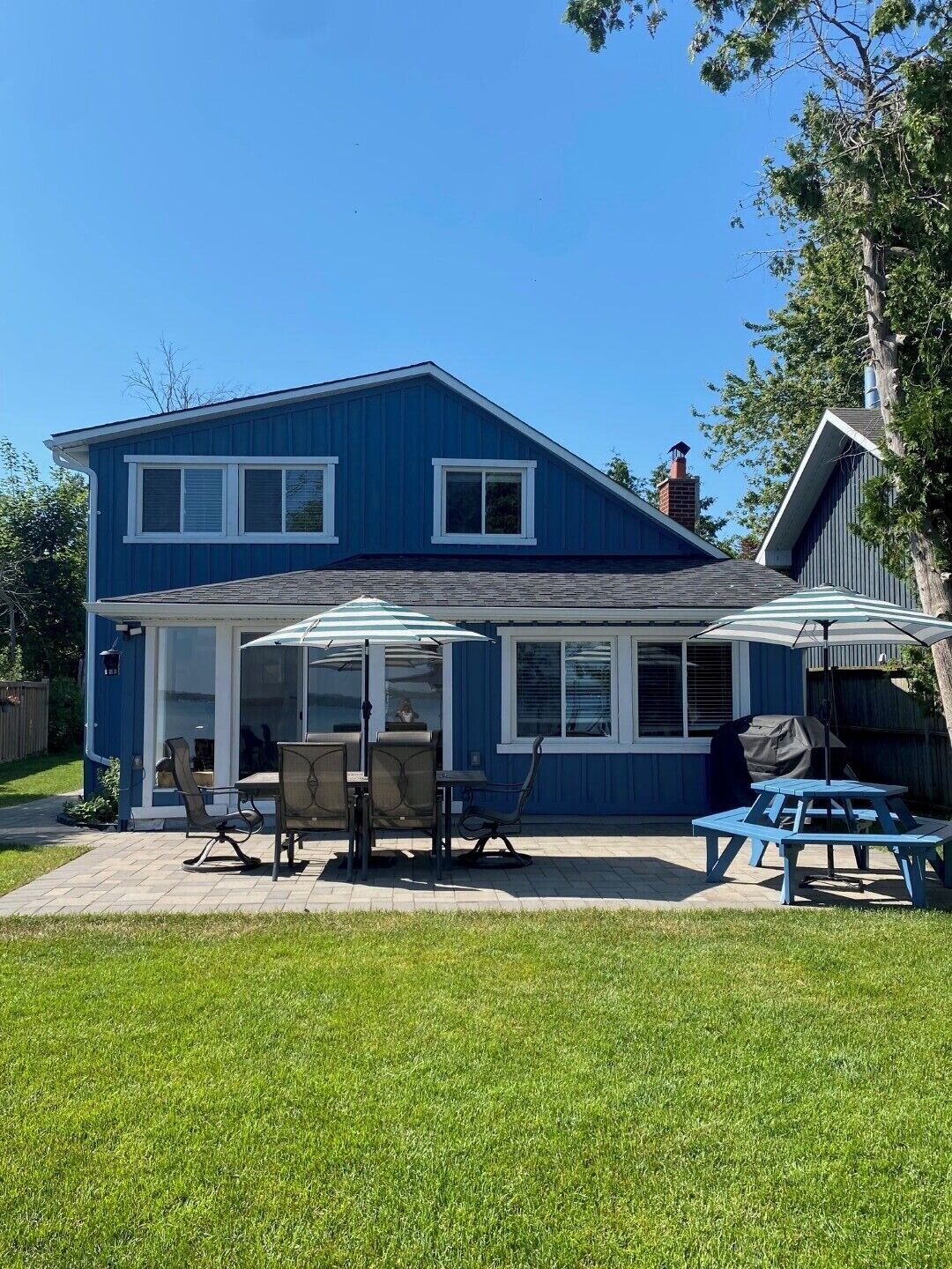A two-story blue house with a patio area featuring outdoor furniture and a covered seating area.