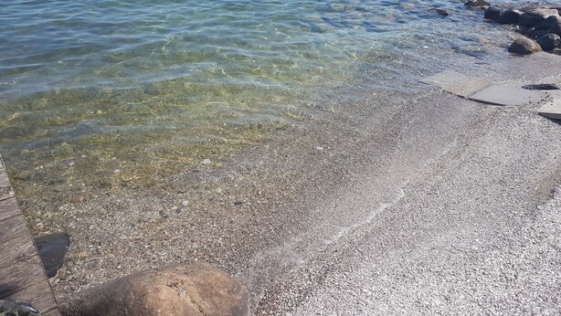 A pebbled beach with clear water, a concrete slab, and a large rock. - Amazing Waterfront, Cottage at Big Bay Point (Innisfil)