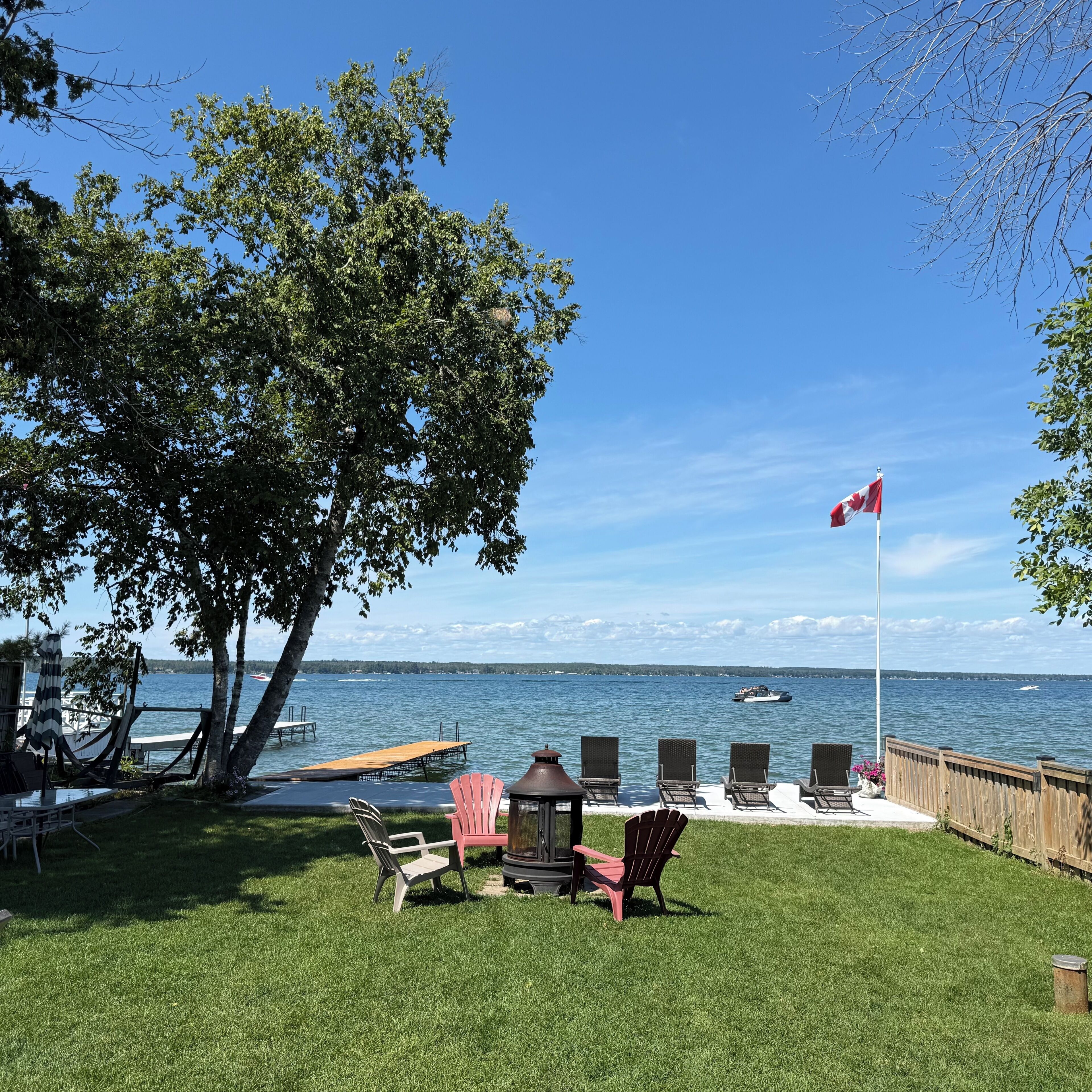 A waterfront patio with chairs, a flag, and a view of the water.