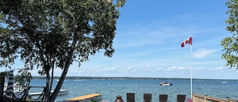 A waterfront patio with chairs, a flag, and a view of the water.