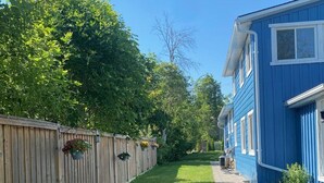 A residential property with a well-maintained lawn, a wooden fence, and a blue house with white trim. - Amazing Waterfront, Cottage at Big Bay Point (Innisfil)