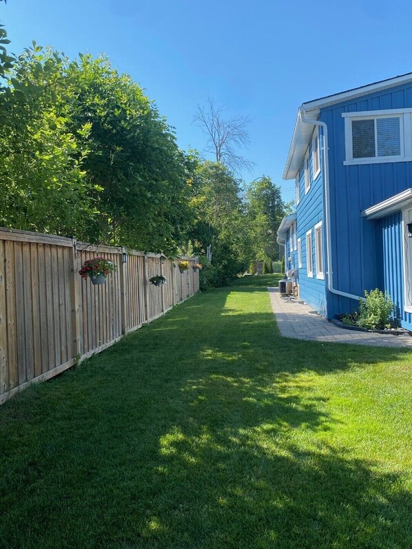 A residential property with a well-maintained lawn, a wooden fence, and a blue house with white trim. - Amazing Waterfront, Cottage at Big Bay Point (Innisfil)
