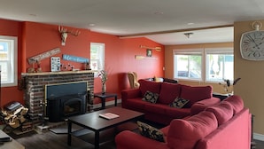 A living room with a fireplace, red sofa, and decorative items on the walls. - Amazing Waterfront, Cottage at Big Bay Point (Innisfil)