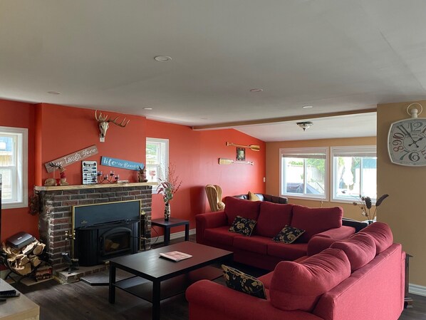 A living room with a fireplace, red sofa, and decorative items on the walls.