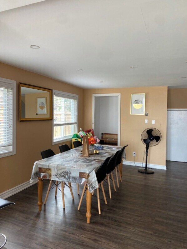 A dining area with a long table, chairs, and a fan.