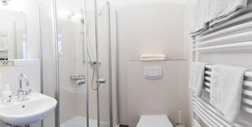 Ein modernes Badezimmer mit einer Duschkabine aus Glas, einem weißen Waschbecken und einem Handtuchhalter.
